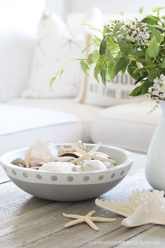 a white vase filled with flowers sitting on top of a table next to a bowl