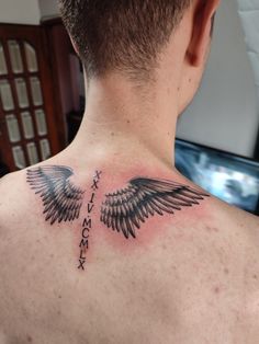 the back of a man's neck with an angel wing tattoo on his chest