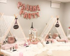 a pink party with teepee tents and decorations on the floor, including letters that read pajama party