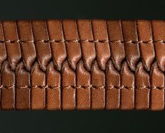 a close up view of the leather texture on a piece of brown material with braiding