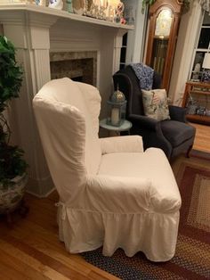 a living room filled with furniture and a fire place covered in a white chair cover