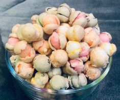 a glass bowl filled with different colored candies on top of a gray tablecloth