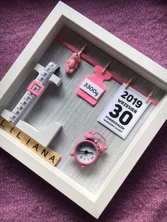 a pink clock and other items are in a shadow box on a purple carpeted surface