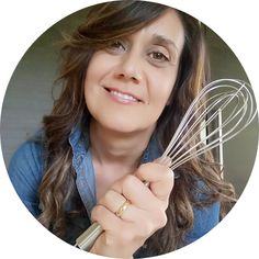 a woman holding a whisk and looking at the camera