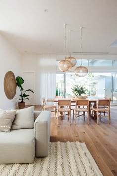 a living room filled with furniture next to a wooden table and chairs on top of a hard wood floor