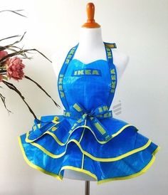 a mannequin wearing a blue and yellow dress next to a vase with flowers