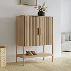 a wooden cabinet with shoes on it in a living room next to a white couch