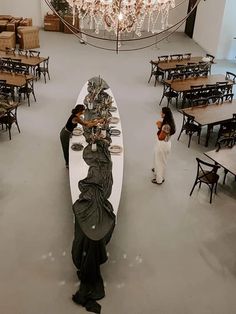 two women standing in front of a long table with food on it and a chandelier hanging from the ceiling