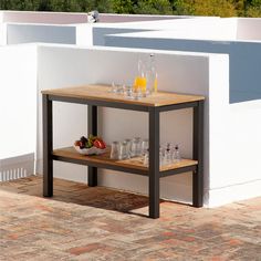 a small table with drinks on it in front of a white wall and brick floor