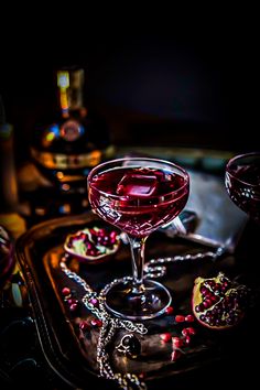 a glass filled with red liquid sitting on top of a tray next to other glasses