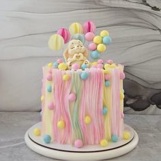 a cake decorated with pastel colors and balloons