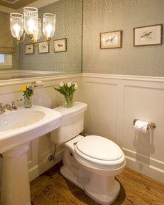 a white toilet sitting next to a sink in a bathroom under a mirror and lights