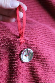 a button on a pink sweater is being held by someone's hand with a red string