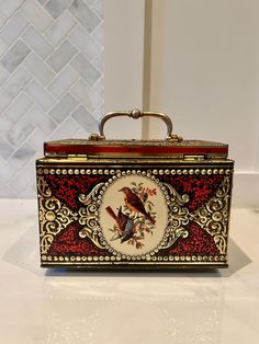 a decorative box with a bird painted on the front and sides, sitting on a counter