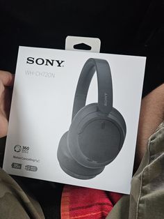 a person holding up a sony wireless headphones in their hand with the box open