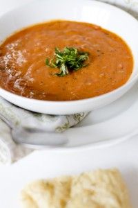 a white bowl filled with soup on top of a plate next to a cracker