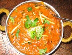 a metal bowl filled with soup and garnished with cilantro on top