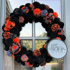 a black and orange wreath sitting on top of a window sill next to a sign