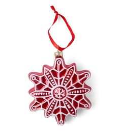 a red ornament hanging from a red ribbon on a white background with an ornate design