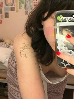 a woman taking a selfie with her cell phone in front of her face and tattoos on her arm