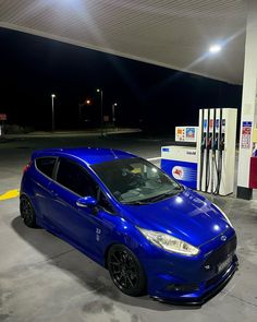 a blue car is parked at a gas station