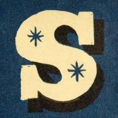 the letter s is painted with black and white paint on a blue carpeted surface