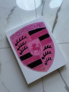 a pink and black sticker on top of a white tile floor next to a vase