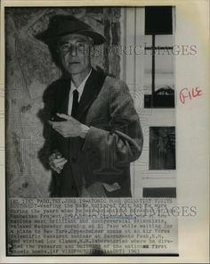 an old black and white photo of a man in a suit pointing to something on the wall