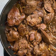 a skillet filled with meat and vegetables on top of a table