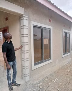 a man standing in front of a house with windows on the outside and walls painted white