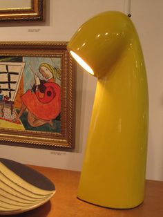 a yellow lamp sitting on top of a wooden table next to a plate and bowl