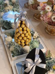 a table topped with boxes filled with chocolates next to flowers and vases full of flowers