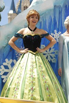 a woman in a green and black dress standing next to another woman wearing a snow queen costume