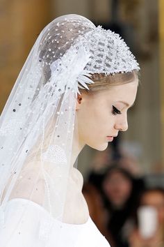 a woman with a veil on her head wearing a white wedding dress and tiara