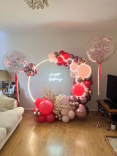 balloon arch with happy birthday sign and balloons in front of it on wooden flooring