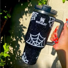 a person holding a cup in front of a brick wall with spider webs on it