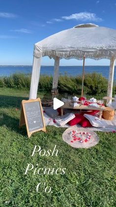 a white gazebo sitting on top of a lush green field next to the ocean