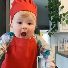 a little boy wearing an apron and a red hat making a funny face with his tongue out