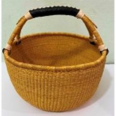 a woven basket with black handles on a white surface