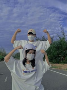 a man and woman wearing face masks while standing in the middle of an empty road