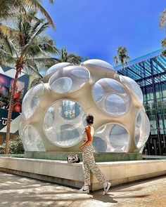 a woman walking in front of a giant bubble like structure