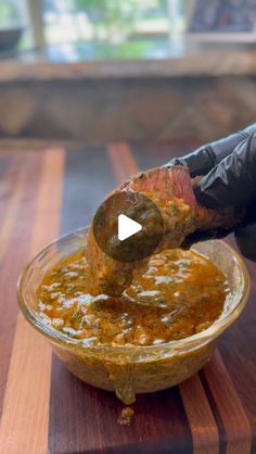 a person in black gloves is dipping something into a glass bowl with food on it