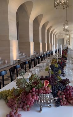 a long table is set with grapes and wine glasses for a formal dinner or function