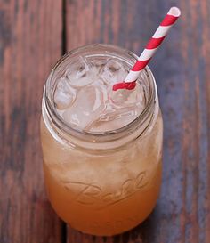 a mason jar filled with ice and topped with a red and white striped straw sitting on top of a wooden table