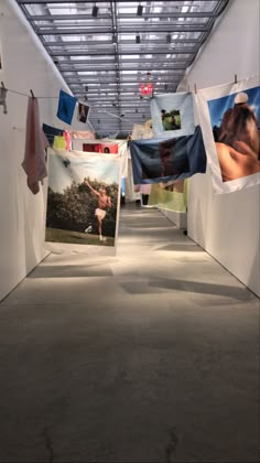 an art gallery with multiple pictures hanging from the ceiling and clothes hung up to dry