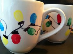 two coffee mugs with christmas lights painted on them