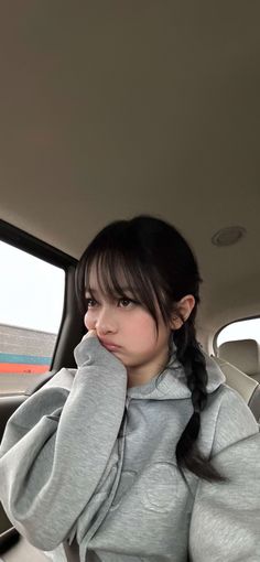 a woman sitting in the back seat of a car with her hand on her head