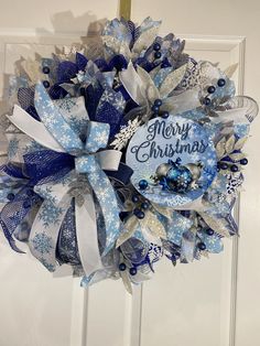 a blue and white christmas wreath hanging on a door