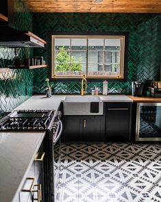 a kitchen with black and white tile flooring and green wallpaper on the walls