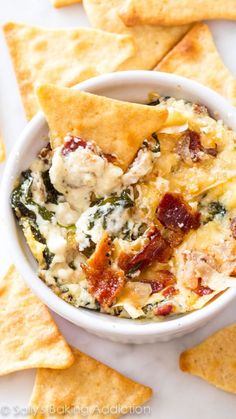 a white bowl filled with cheese and spinach dip next to crackers on the side